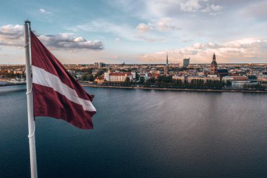 Aerial panorama of Riga city with a big Latvian flag in the foreground. Golden hour. clipart