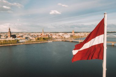 Ön planda büyük bir Leton bayrağı ile Riga şehrinin havadan panoraması. Altın saat.