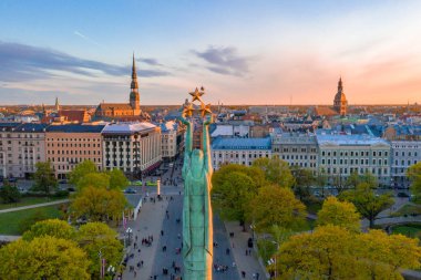 Letonya Milda - Özgürlük heykeli tarafından Riga üzerinde güzel günbatımı görünümü. Özgürlük anıtı. Konser için anıtın etrafında toplanan insanlar.  
