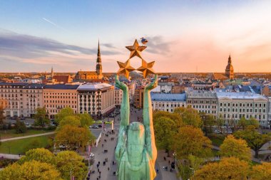 Letonya Milda - Özgürlük heykeli tarafından Riga üzerinde güzel günbatımı görünümü. Özgürlük anıtı. Konser için anıtın etrafında toplanan insanlar.  
