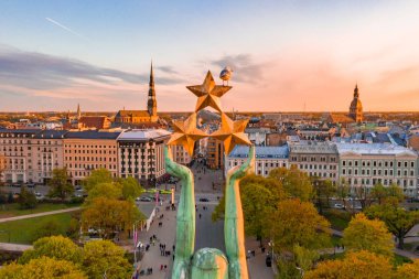 Letonya Milda - Özgürlük heykeli tarafından Riga üzerinde güzel günbatımı görünümü. Özgürlük anıtı. Konser için anıtın etrafında toplanan insanlar.  