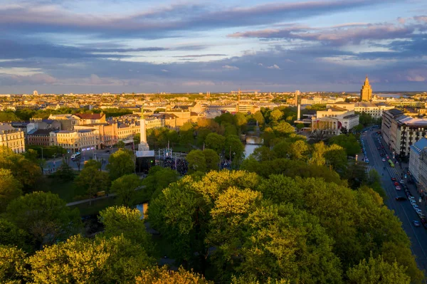 Letonya Milda - Özgürlük heykeli tarafından Riga üzerinde güzel günbatımı görünümü. Özgürlük anıtı. Konser için anıtın etrafında toplanan insanlar. 