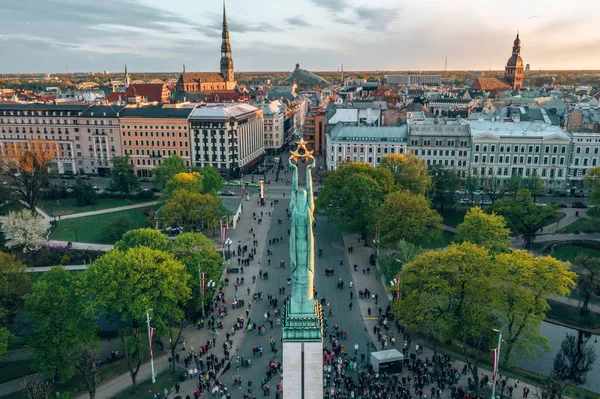 Letonya Milda - Özgürlük heykeli tarafından Riga üzerinde güzel günbatımı görünümü. Özgürlük anıtı. Konser için anıtın etrafında toplanan insanlar. 