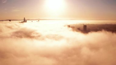 Rising and flying over the clouds during morning sunrise in San Francisco with skyscrapers rising above the clouds. Beautiful California, San Francisco.
