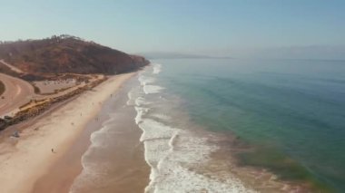 Beautiful aerial view of the Pacific ocean coastline with huge waves by the beach.