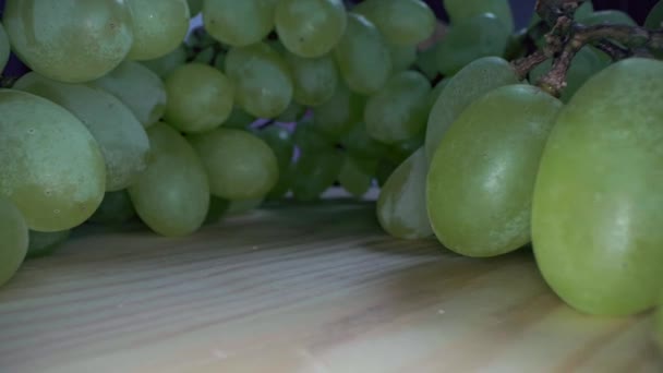 マクロウォータースプラッシュのブドウベリーのビューを閉じます 透明な水滴で覆われた緑のブドウの束は カメラの前でゆっくりと回転します — ストック動画