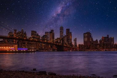 Brooklyn Parkı 'ndan Brooklyn Köprüsü' nün büyülü akşam mor gün batımı manzarası Hudson Nehri 'nin diğer tarafındaki Manhattan manzaralı..