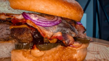 Et pirzolası, soğan, sebze, erimiş peynir, marul ve mayonez soslu büyük iştah açıcı burger. İzole edilmiş hamburger koyu duman arka planında döner, yakın plan görüntüsü