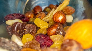 Fındık, tohum ve kurumuş meyvelerin cam bir kavanozda ve ahşap bir masada makro görüntüsü.