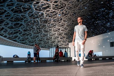Abu Dabi, Birleşik Arap Emirlikleri, 20 Mayıs 2020: Abu Dabi 'de Louvre' da oturan genç adam sanatını araştırıyor..
