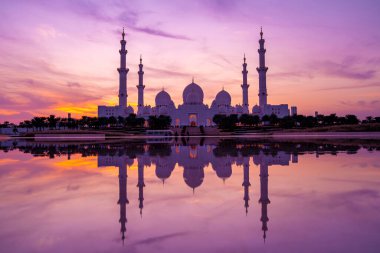 Günbatımında Abu Dabi 'deki Büyük Cami' nin büyülü mor günbatımı. Şeyh Zayed Camii 'nin dış görünümü BAE.
