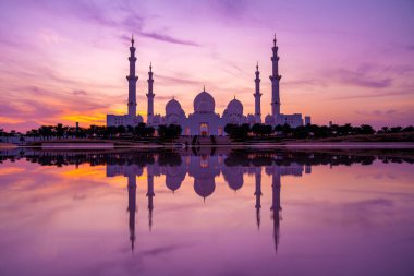 Günbatımında Abu Dabi 'deki Büyük Cami' nin büyülü mor günbatımı. Şeyh Zayed Camii 'nin dış görünümü BAE.