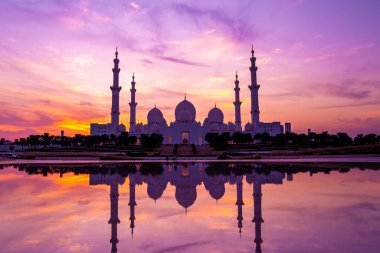 Günbatımında Abu Dabi 'deki Büyük Cami' nin büyülü mor günbatımı. Şeyh Zayed Camii 'nin dış görünümü BAE.