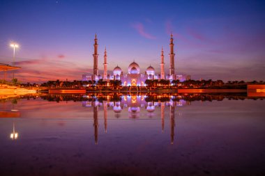 Günbatımında Abu Dabi 'deki Büyük Cami' nin büyülü mor günbatımı. Şeyh Zayed Camii 'nin dış görünümü BAE.