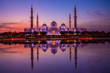 Günbatımında Abu Dabi 'deki Büyük Cami' nin büyülü mor günbatımı. Şeyh Zayed Camii 'nin dış görünümü BAE.