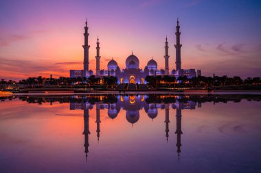 Günbatımında Abu Dabi 'deki Büyük Cami' nin büyülü mor günbatımı. Şeyh Zayed Camii 'nin dış görünümü BAE.