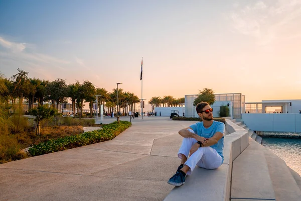 ルーブル アブダビ アラブ首長国連邦 2020年5月10日 アブダビのルーブルのそばに座っている若い男 夕日の美しい建物 — ストック写真