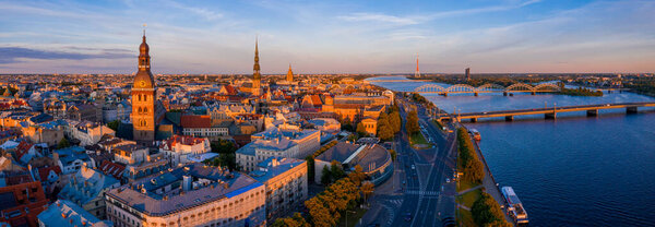 Flying over beautiful old town of Riga, Latvia at sunset with Domes cathedral. Panoramic aerial view.