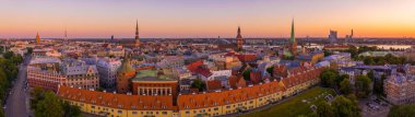 Riga Center 'ın güzel hava manzarası ve Daugava nehri üzerindeki Vansu köprüsü gün batımında. Letonya 'nın başkenti Riga' nın aydınlanmış manzarası.