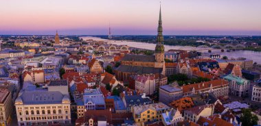 Riga Center 'ın güzel hava manzarası ve Daugava nehri üzerindeki Vansu köprüsü gün batımında. Letonya 'nın başkenti Riga' nın aydınlanmış manzarası.