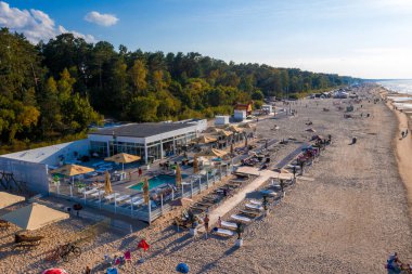 Dzintari, Jurmala, Letonya - 12 Ağustos 2020: İnsanlar Jurmala tatil beldesi X.O. 'daki Baltık Körfezi sahilindeki güneşli bahar gününün tadını çıkarıyorlar. Letonya 'daki restoran.