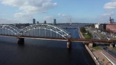 Letonya 'nın başkenti Riga' daki Daugava nehri boyunca uzanan trafik köprüsünün panoramik bir videosu..