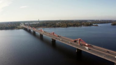 Letonya 'nın başkenti Riga' daki Daugava nehri boyunca uzanan trafik köprüsünün panoramik bir videosu..