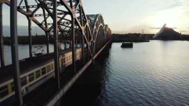 Gün batımında Letonya Riga 'daki Daugava Nehri üzerinden Demir Köprü' yü geçen bir tren. Riga 'da güzel bir köprü manzarası.