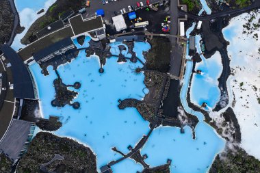 İzlanda 'daki Mavi Göl Kaplıcaları' nın hava manzarası sütlü mavi jeotermal havuzlar, volkanik lav alanları, modern tesisler ve dolambaçlı yollar..