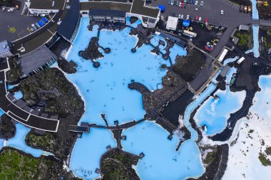 Süt mavisi suları, siyah lav tarlaları, spa tesisleri, patikalar, lavlardan etkilenen yollar ve İzlanda 'daki park halindeki araçlarla jeotermal kaplıca..