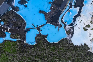 Mavi Lagoon Spa 'nın sütlü mavi jeotermal suları siyah lav tarlaları, modern tesisler ve İzlanda' nın engebeli arazisinde yükselen buharla çevrilidir..