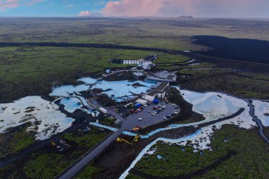 Blue Lagoon Spa 'nın sütlü mavi havuzları, Blue Lagoon Oteli' nin yakınlarındaki koyu lav tarlalarıyla tezat oluşturuyor ve yollar lav akıntılarıyla kısmen tıkanmış durumda..