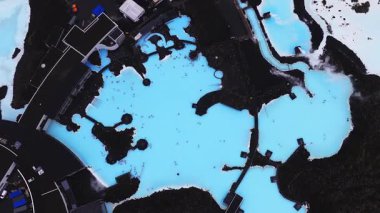 İzlanda 'daki Mavi Göl Kaplıcaları' nın hava manzarası, parlak mavi jeotermal sular, siyah lav alanları, yükselen buhar ve entegre yürüyüş yolları..