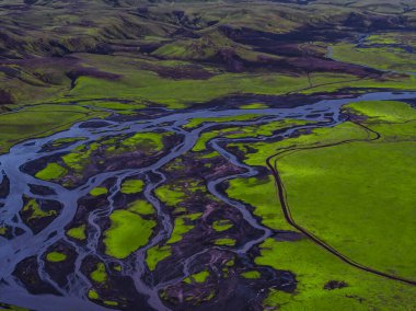İzlanda 'nın yeşil yosunlarının hava manzarası karanlık volkanik topraklarla kaplı, kıvrımlı nehirler ve yuvarlanan tepeler karmaşık doğal desenler yaratıyor..