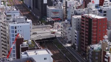 Tokyo, Japonya 'nın havadan görünüşü, modern binaları, bir demiryolu hattını ve şehir manzarasının ortasında yavaş çekimli büyük yeşil bir parkı gösteriyor..
