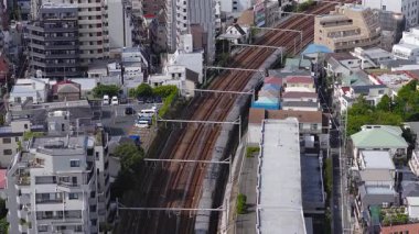 Tokyo, Japonya 'nın gökdelenleri, vinçleri, daha küçük yapıları ve açık mavi gökyüzünün altındaki uzak dağları yavaş çekimde gösteriyor..