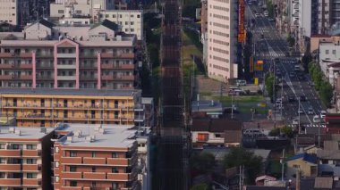 Osaka, Japonya 'nın havadan görünüşü, gökdelenler yüksek binalar, renkli tabelalar, yeşil sokaklar ve hareket halindeki inşaat vinçleri..