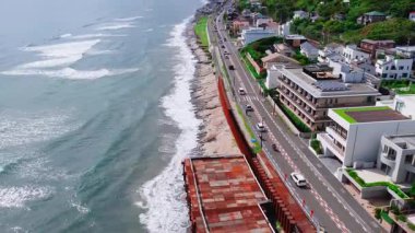 Japonya 'daki Kamakuro kasabasının havadan görünüşü bir kıyı yolu, okyanus dalgaları, bir yamaç yerleşim alanı ve köprüye bağlı bir ada gösteriyor..