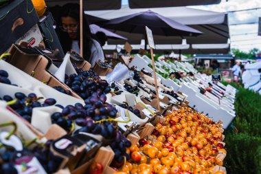 Danimarka 'nın Kopenhag şehrinde canlı bir pazar sahnesi. Tahta kasalarda taze meyveler, şemsiyeli gölgeli tezgahlar ve arka planda bir satıcı var..