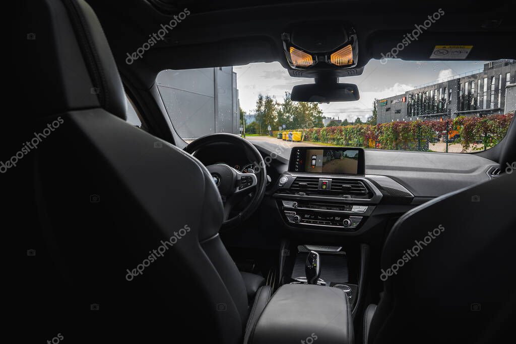Close view of BMW X4 interior showing dashboard with infotainment screen, air vents, control panel, steering wheel, and outdoor scenery through windshield.