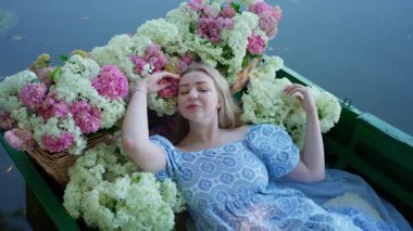 Pembe ve beyaz çiçeklerle çevrili güzel genç bir kadın, kapalı gözlü romantik bir yaz portresi, suda çiçeklerle süslenmiş rüya gibi bir kadın yaşam tarzı sahnesi.