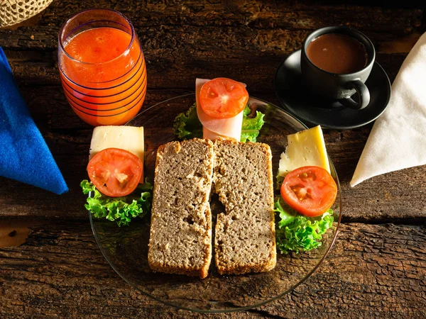 Homemade bread without gluten ready to prepare a sandwich with lechucha, cheese, ham and tomato. And, to drink, papaya juice and chocolate, for breakfast