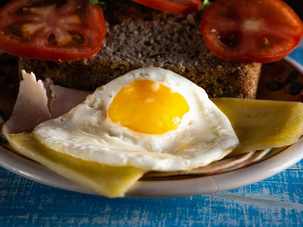 Egg at breakfast, with gluten-free bread, cheese, ham and tomato