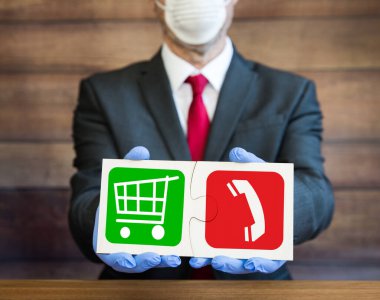 Perakende alışveriş arabası ve cep telefonuyla bir yapboz işareti tutan bir işadamı, Coronavirus salgını sırasında çevrimiçi mağazaların karşılaştığı zorlukları gösteriyor.