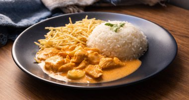 Tavuklu strogonoff, pilav ve patates kızartması. Tavuk stroganoff, Brezilya 'da domates özü, pirinç ve patates cipsi ile yoğun kremadan oluşan Rus mutfağından gelen bir yemektir.