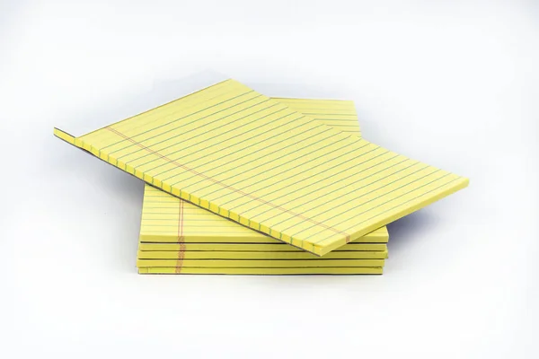 Yellow, ruled notepads neatly stacked with the top one offset that could be used for taking notes, or sharing ideas in school or office settings.