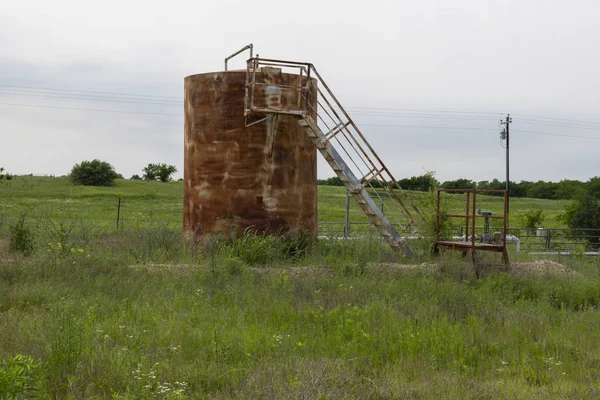 Rusty oil storage tank in a rural farm field