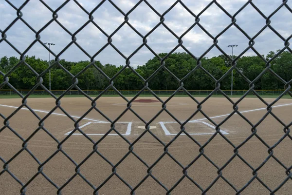 Campo da baseball attraverso la recinzione di collegamento a catena il giorno nuvoloso — Foto Stock