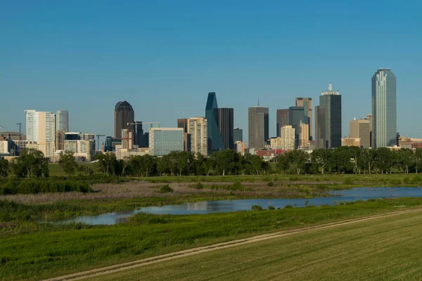 Bazı gökdelenler, ofis kuleleri ve yüksek builisyonlar, su setinden görüldüğü üzere Trinity Nehri havzasının yeşil çimenleri ve ağaçlarıyla Dallas ufuk çizgisini oluşturur..