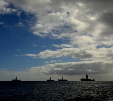 Körfezde dört petrol çıkarma platformları, şafaktan sonra sakin deniz ve bulutlu gökyüzü